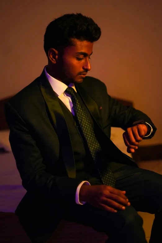 a man in a suit and tie sits down with his arms crossed,