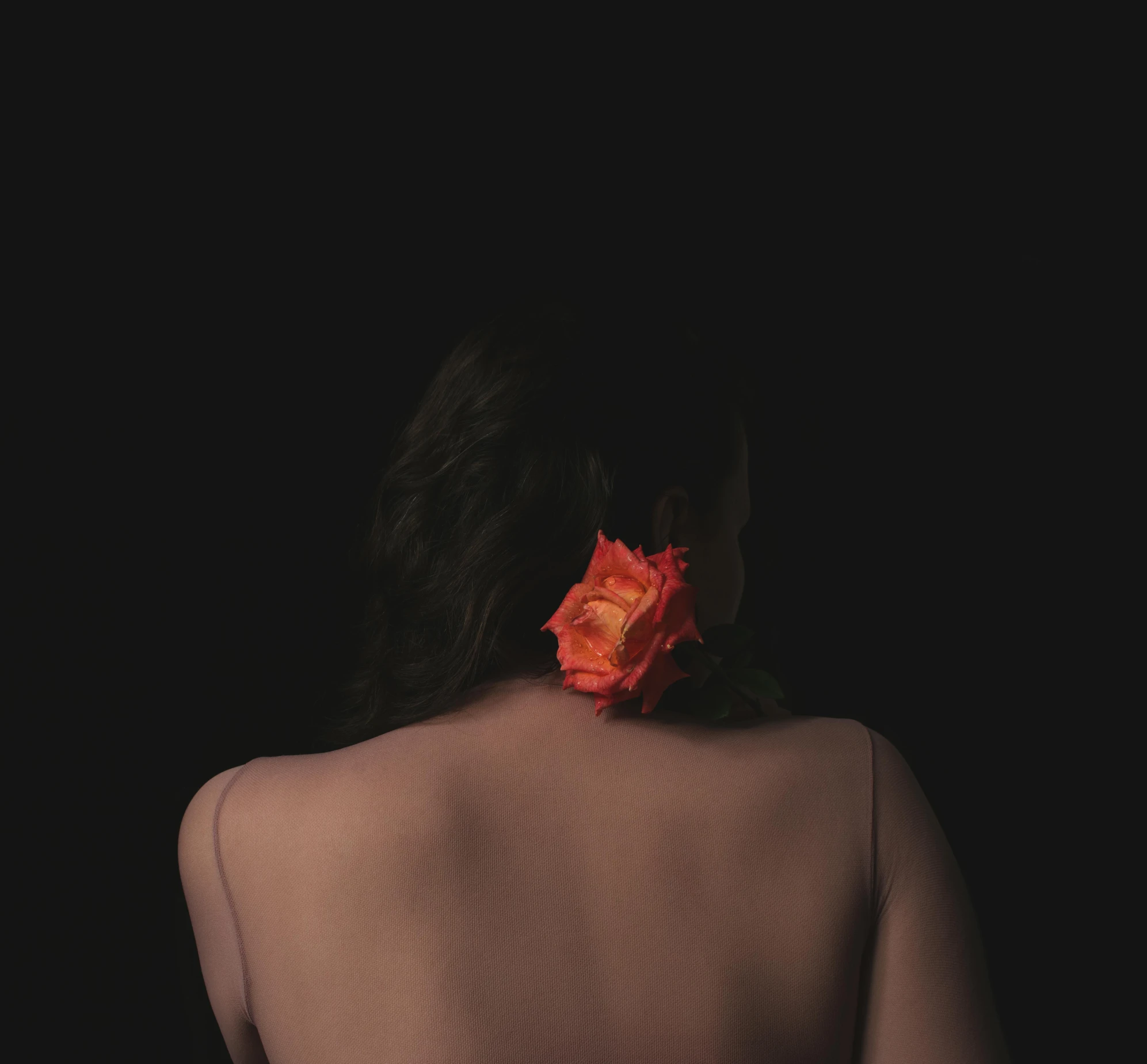 a woman has her back to the camera with a flower in her hair