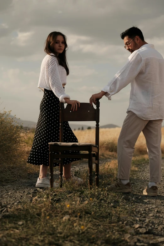 a man and woman holding hands over a small chair