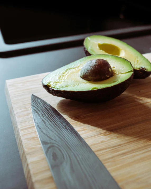 the avocado is on a chopping board ready to be cut