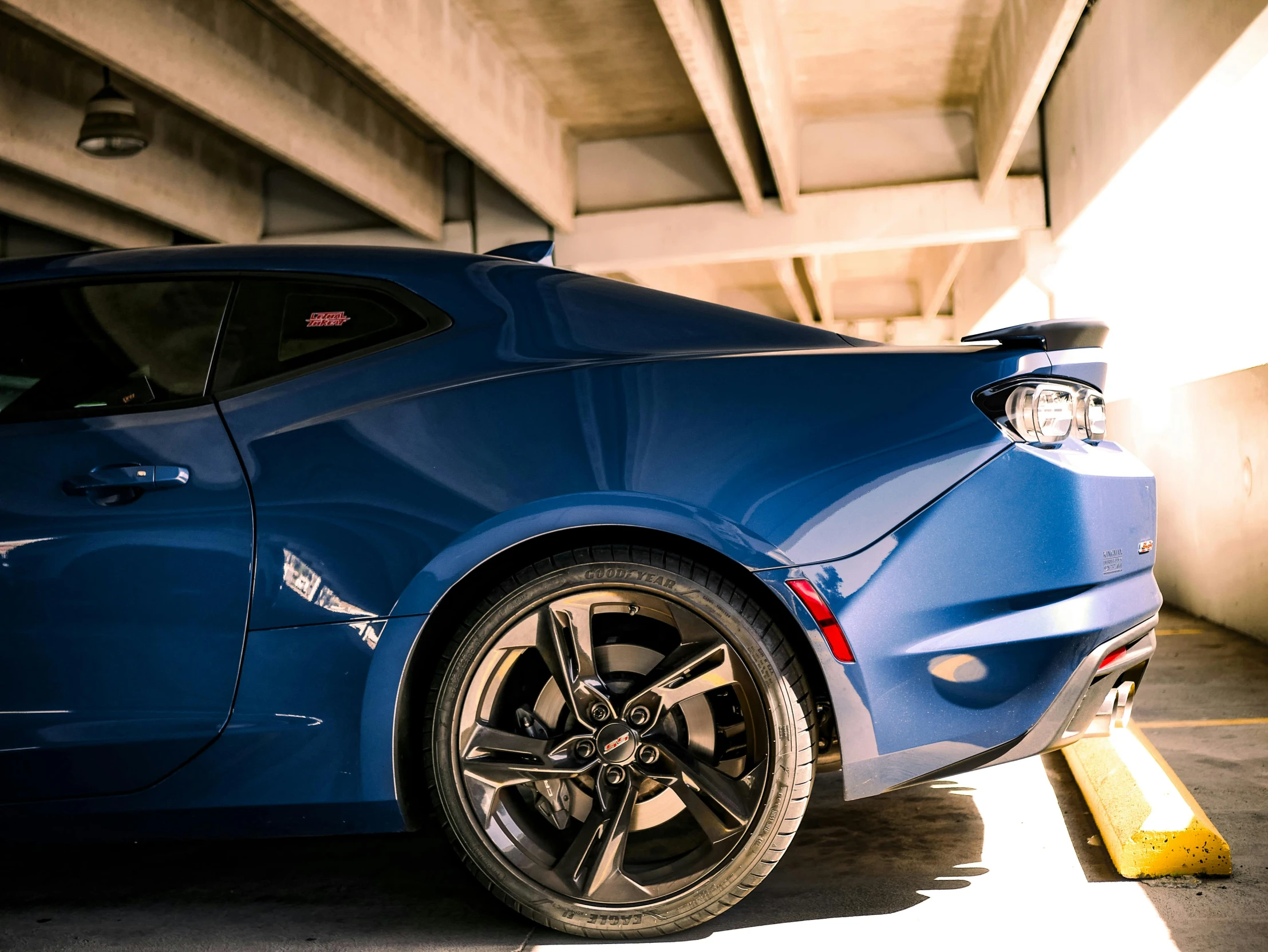 the blue sports car sits next to a yellow pole