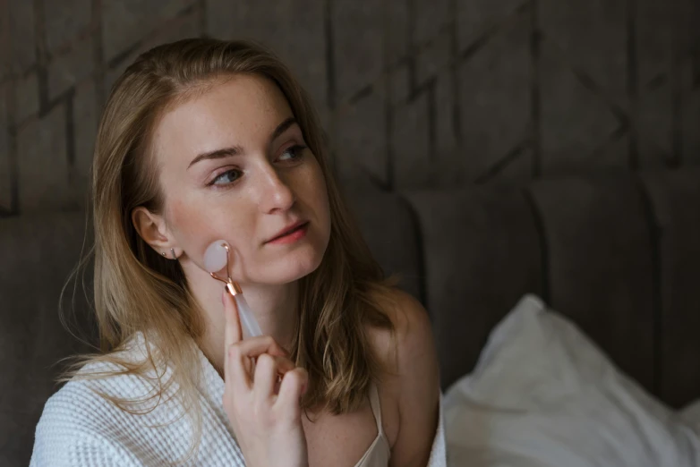 a woman is putting lipstick on her face while looking in the mirror