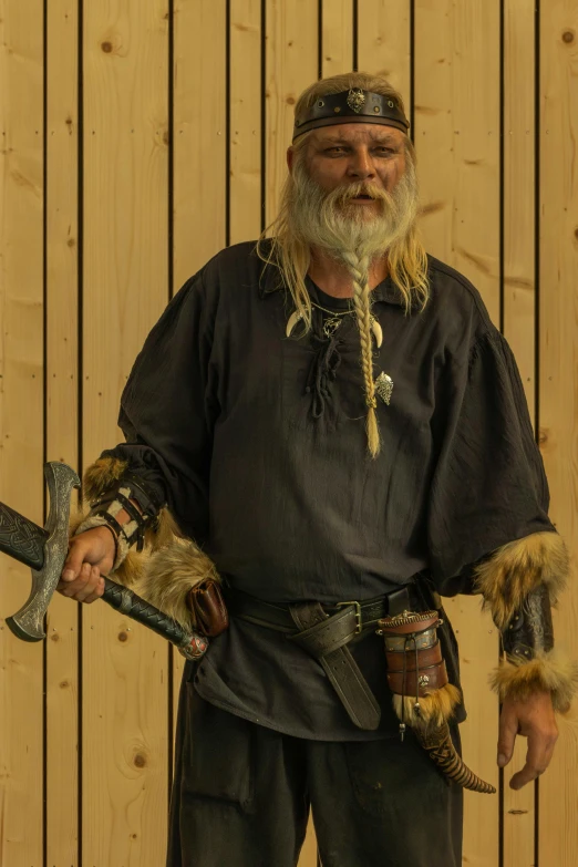a man dressed in viking garb holding a large wrench