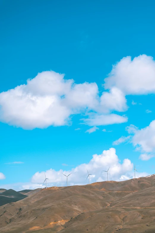 four wind turbines on top of a hill in the countryside