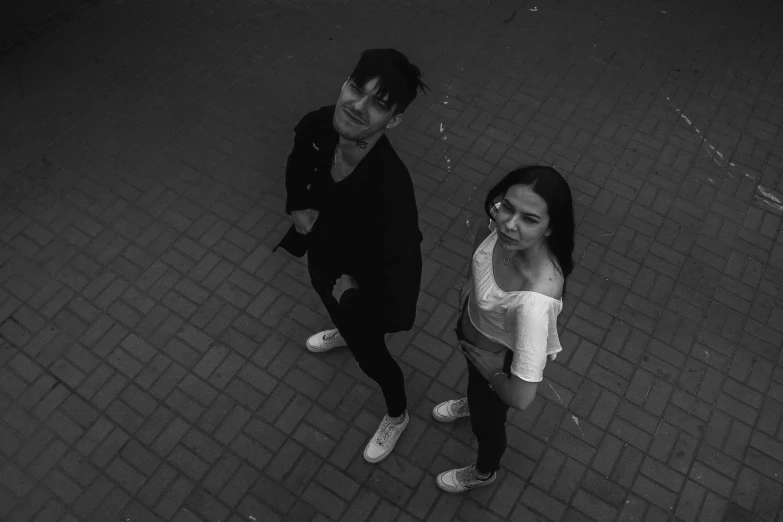 two young people standing on a bricked walkway