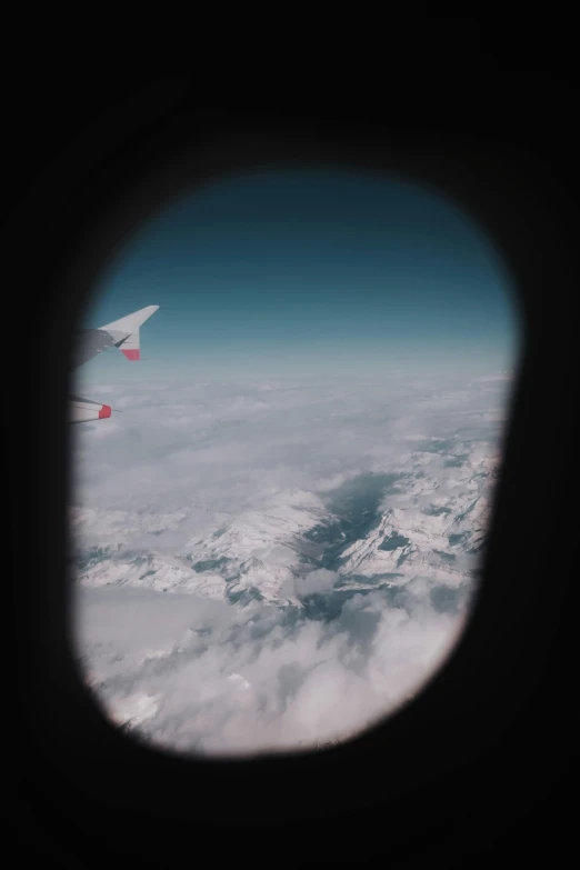 looking out an airplane window at some snow covered mountains