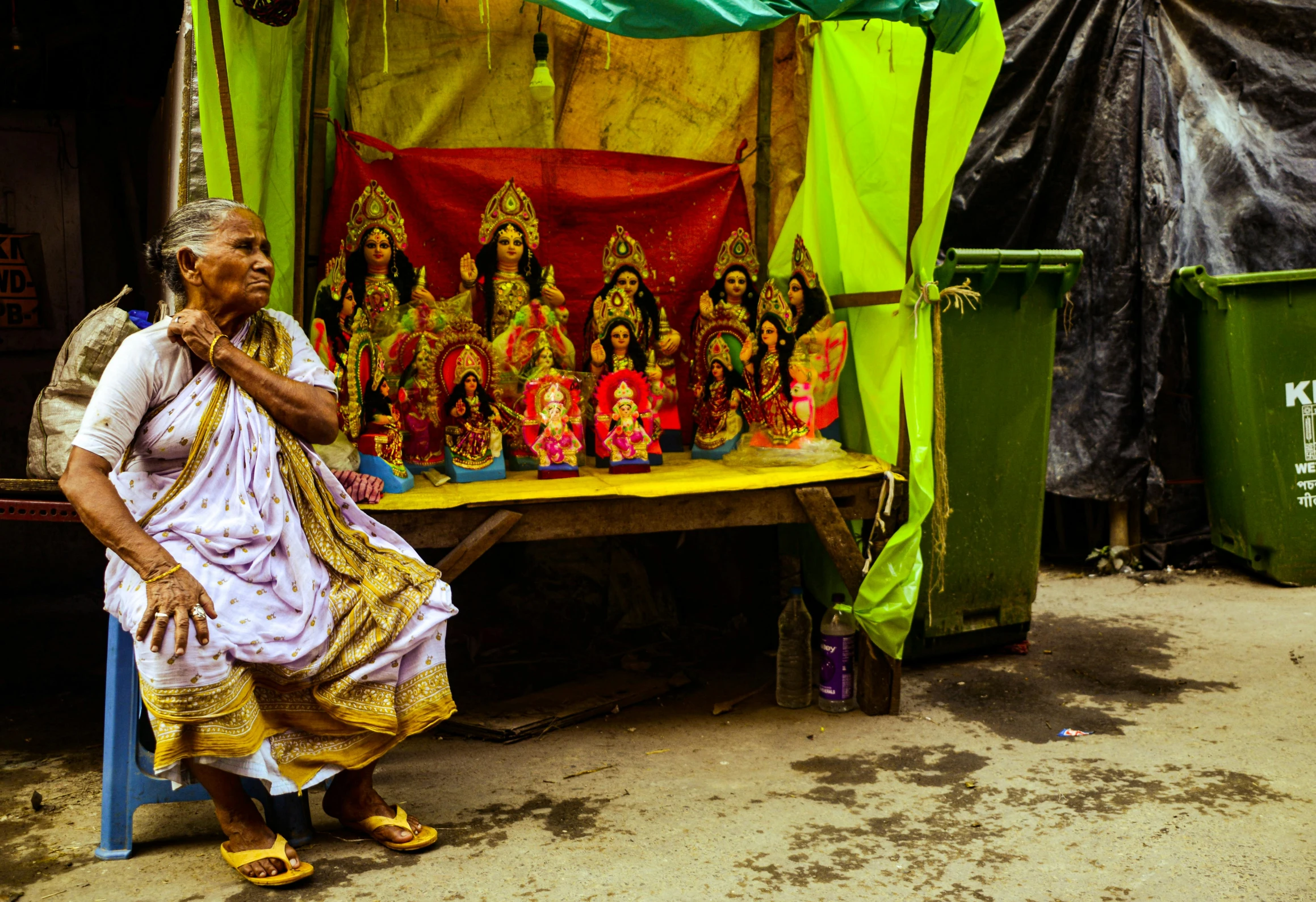 the old man is standing by his shop selling different religious items