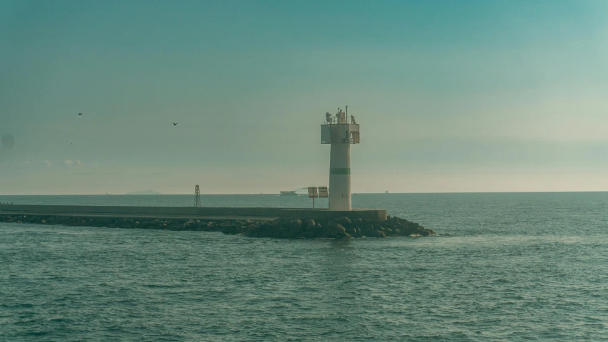 a light house in the middle of water next to a rock