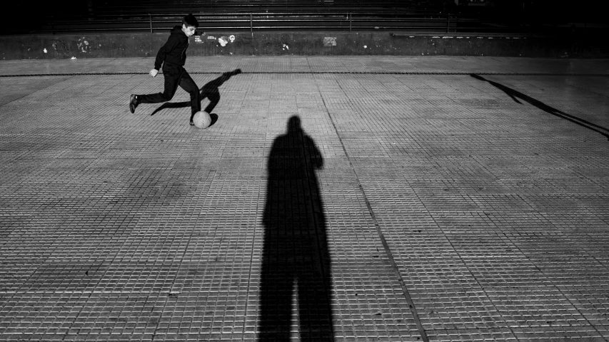 a man walks down the street with his shadow on the ground