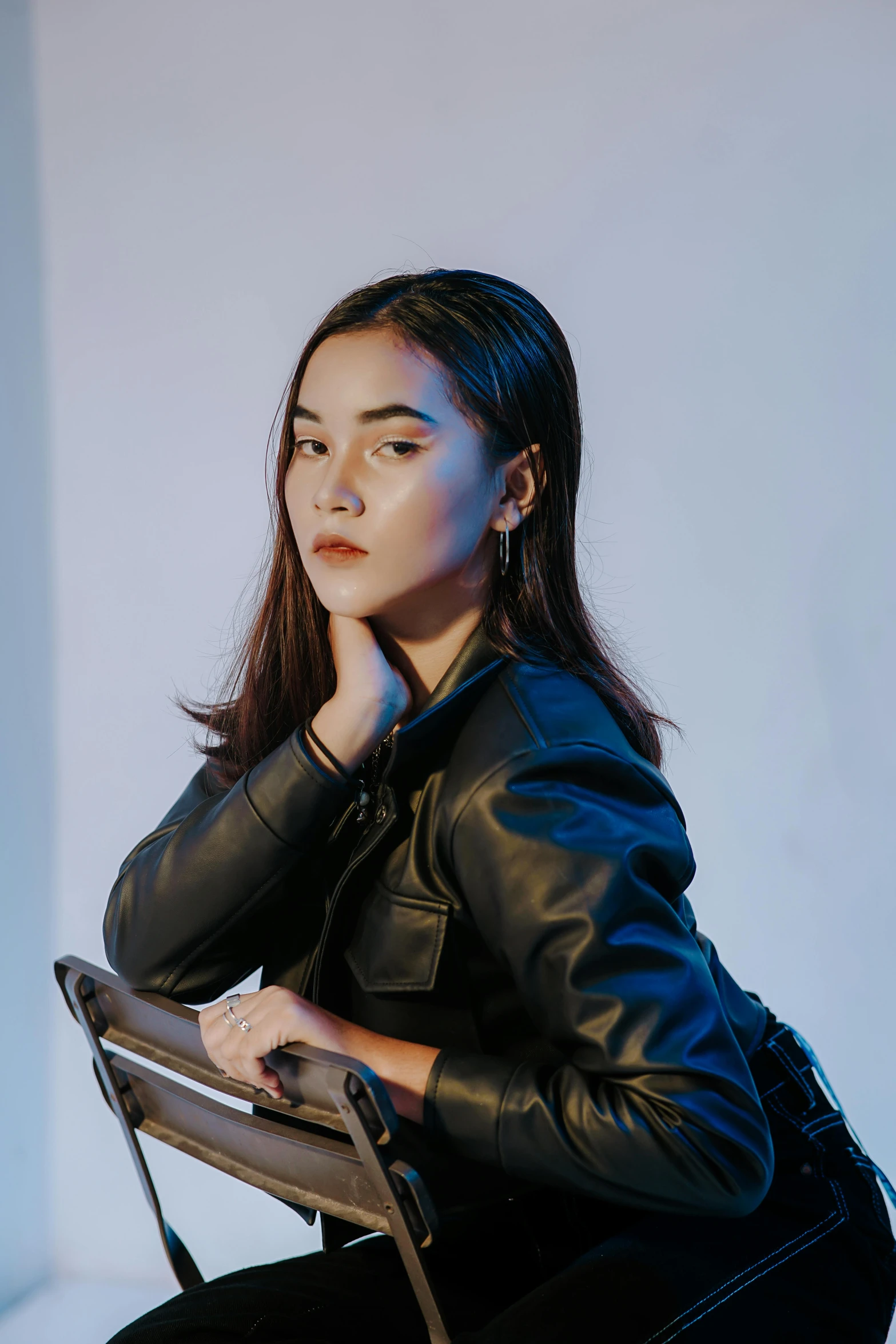 the young woman is sitting on the chair and looking at the camera