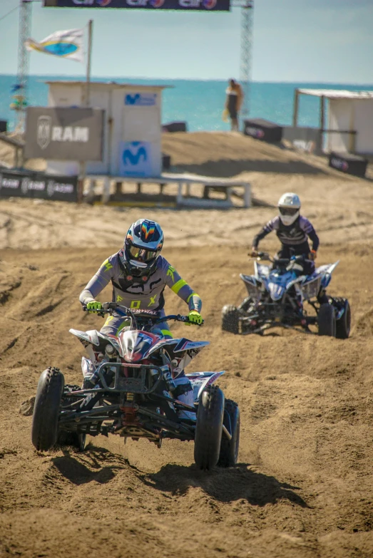 three people riding four wheelers on the dirt