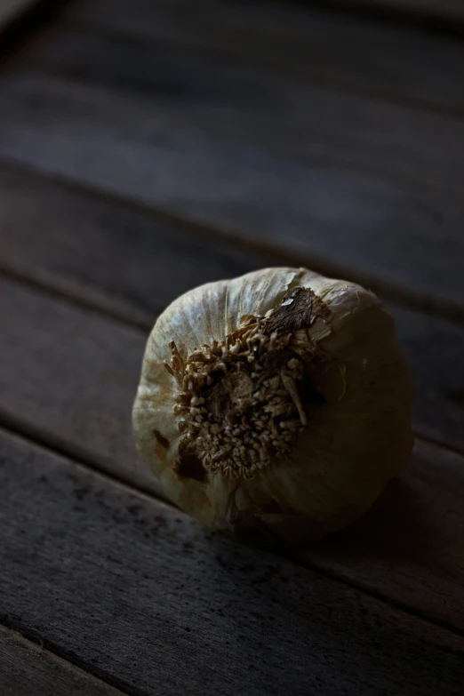 an unpeeled bulb of a onion sitting on a wooden table