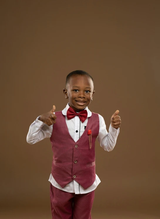 a small child wearing a red vest and bow tie