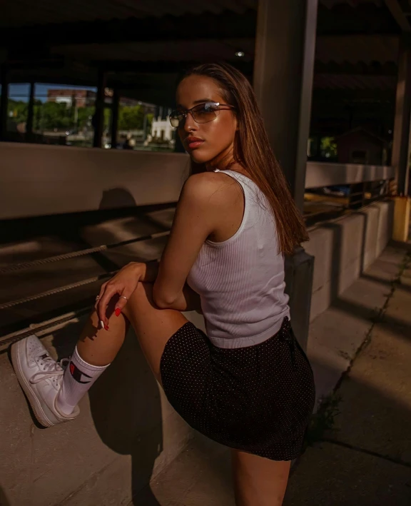 a beautiful woman with sunglasses sitting on the side of a building