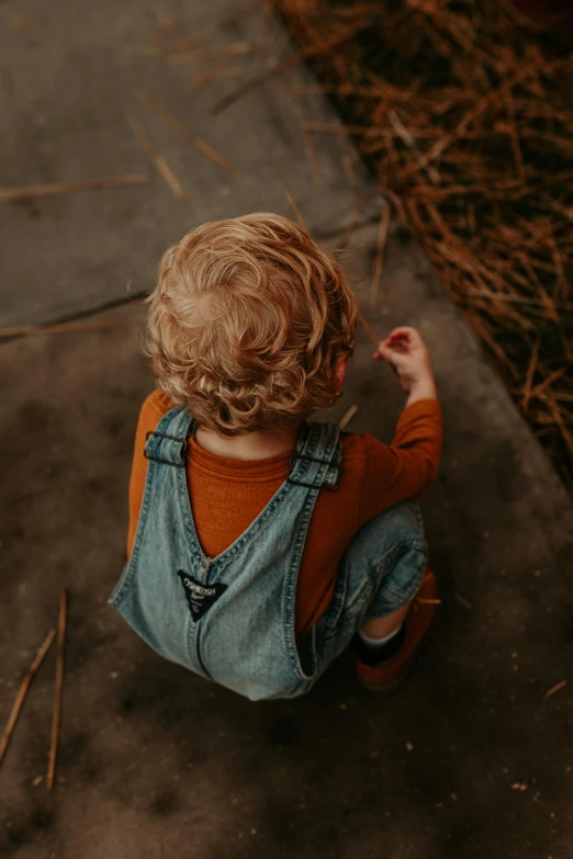 a small child sits on the ground with a string in his mouth