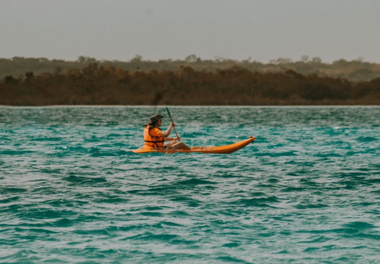 a man on a yellow kayak in the middle of water