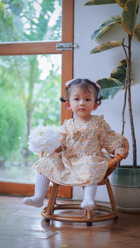 a baby girl sitting on a rocking chair with flowers in her hair