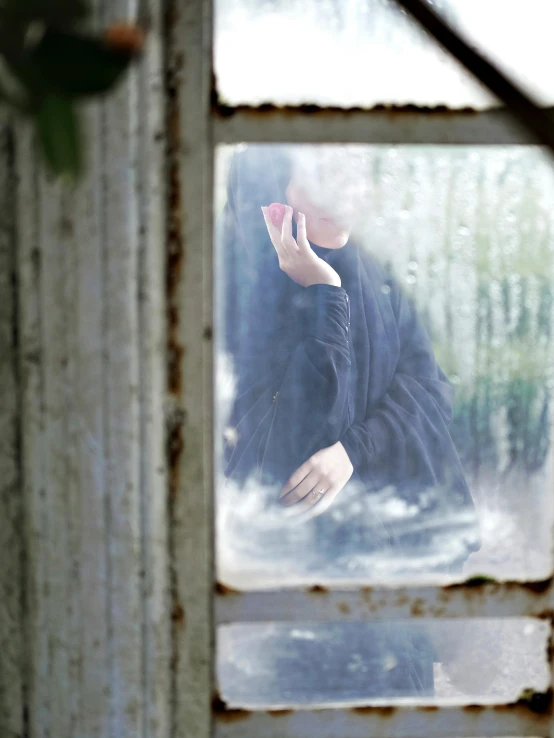 a woman's face is visible through the window of an abandoned structure