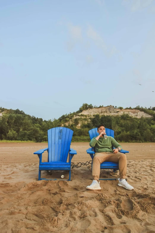 man in green sitting on blue lawn chairs