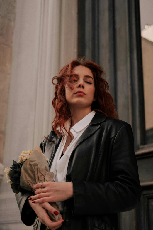 young woman with red hair and white shirt holding a bouquet