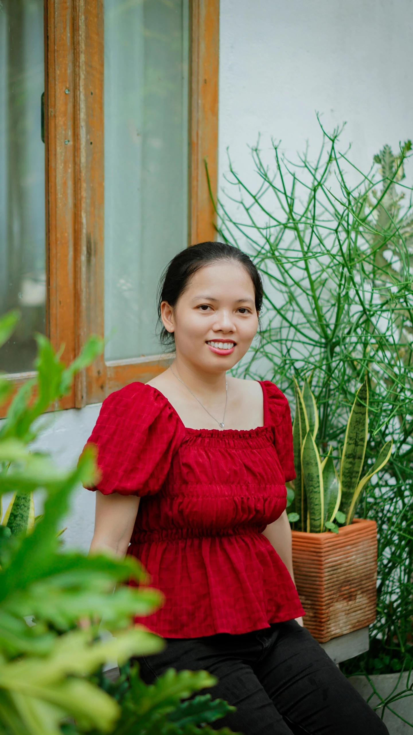 a woman sitting down next to a plant