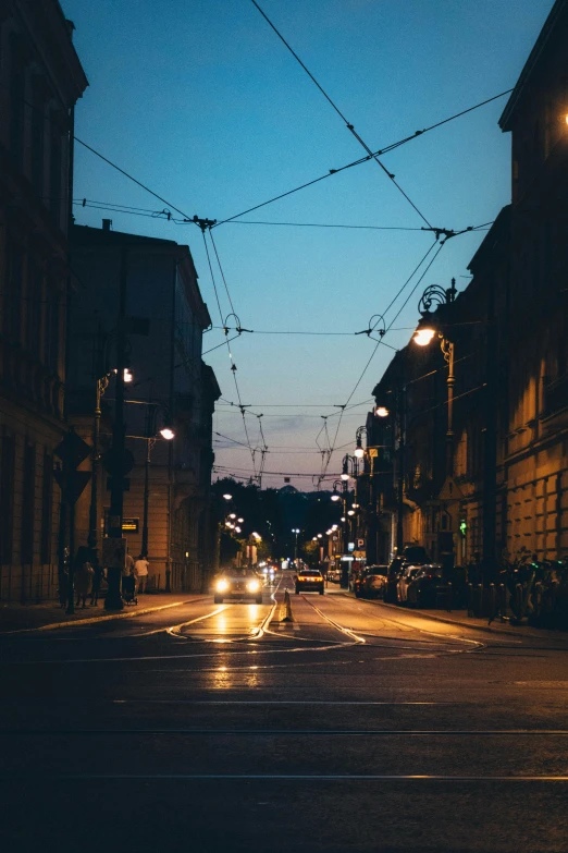 two buildings on the right side of the street and the traffic lights are shining down the middle of the street at night