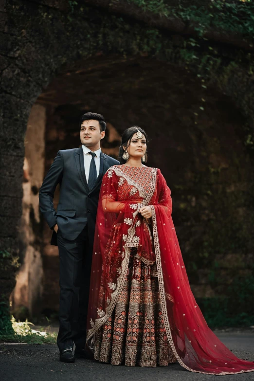 a couple is dressed in a traditional indian outfit standing outside