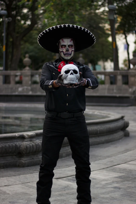 a man in the street wearing a costume holding a skull