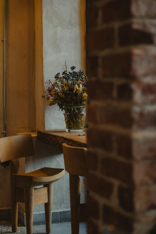 a vase with flowers on a small table next to a window