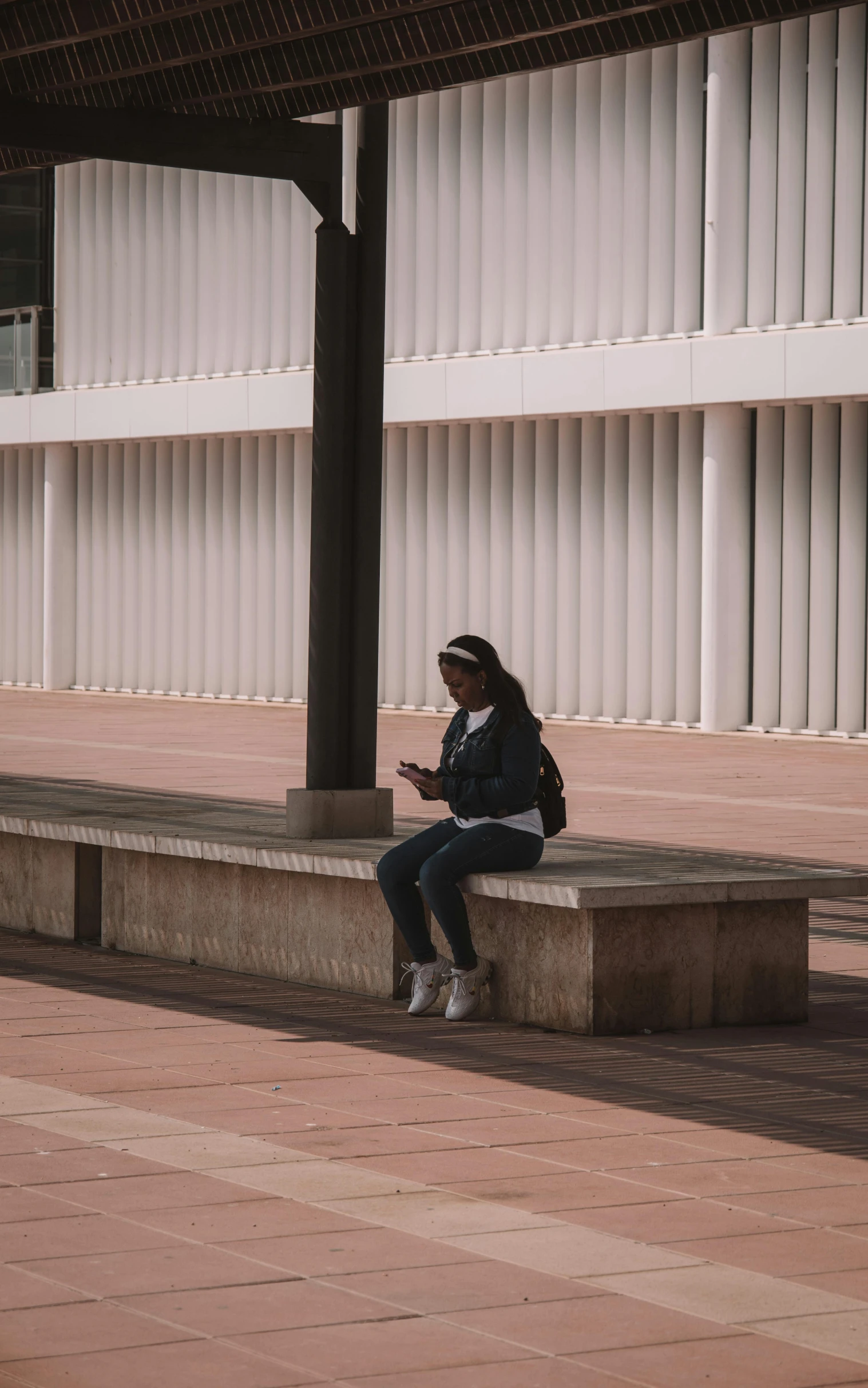 a woman sits on a cement bench and looks at her phone