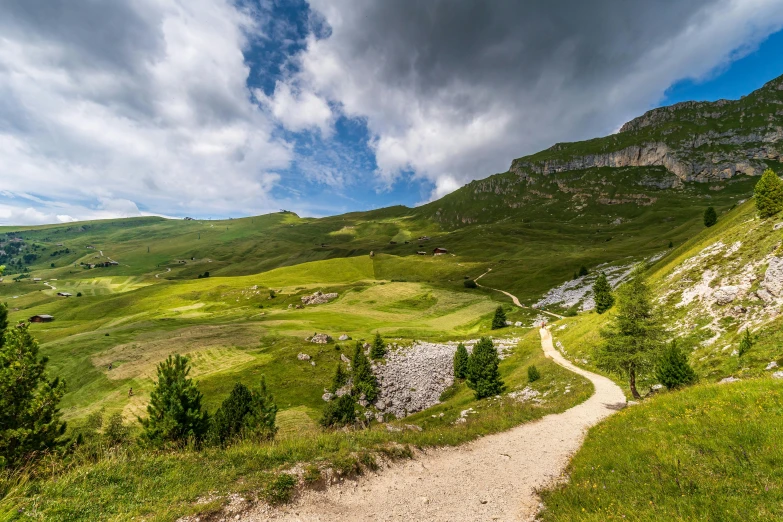 a dirt road leading down into the valley in front of mountains