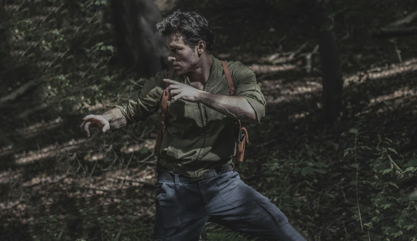 the man has made gestures while walking through a forest