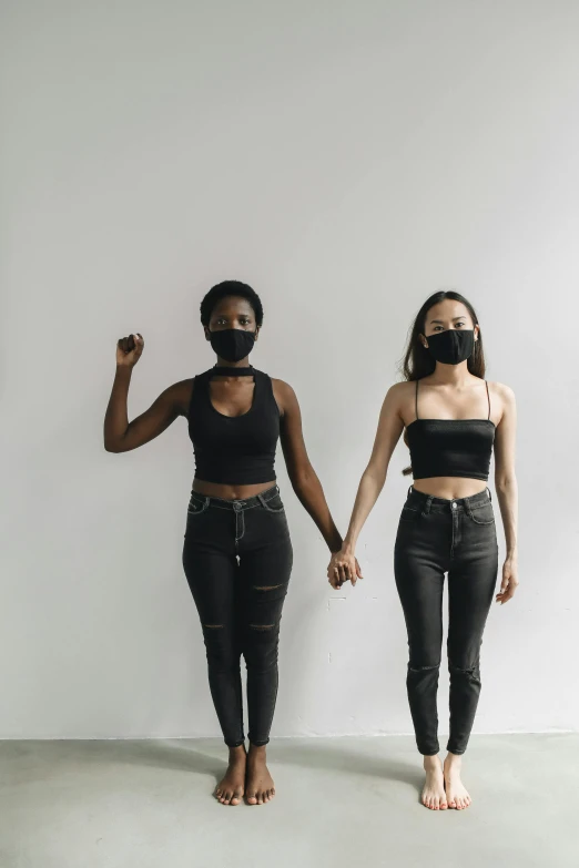 two women in black outfits standing in front of a white wall