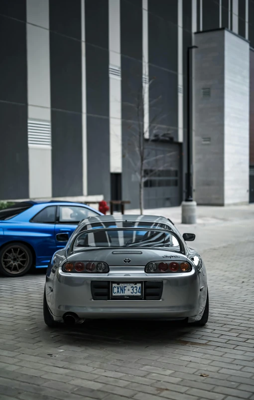 two car parked on a brick sidewalk next to building