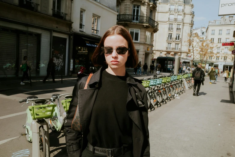 a girl standing on the side walk in front of bicycles