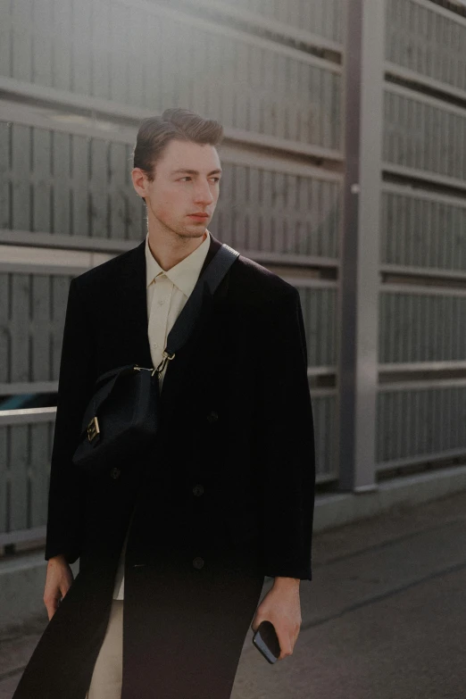 a man walking down a street while holding onto a black bag