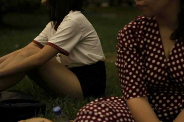 two young women sit in a grassy field