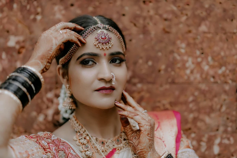 a bride in an indian bridal outfit holding her forehead up