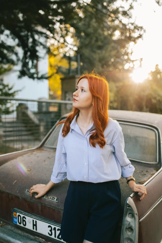 woman standing next to an old car in the middle of the road