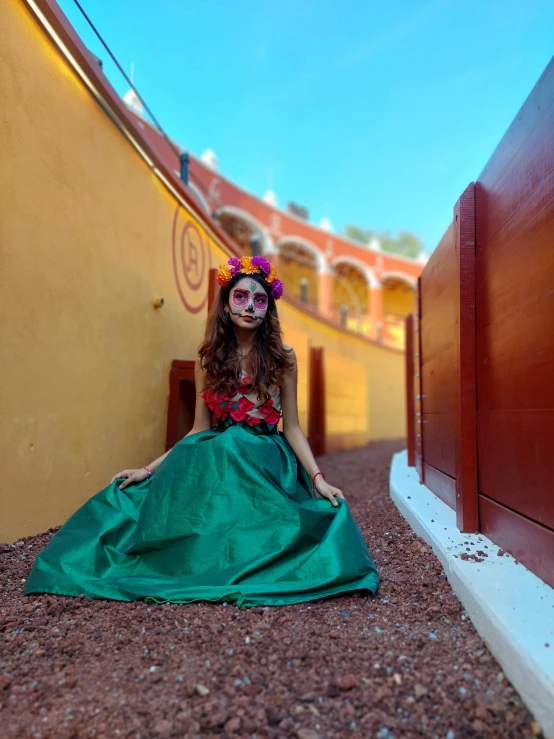 a woman dressed in green sits on the ground