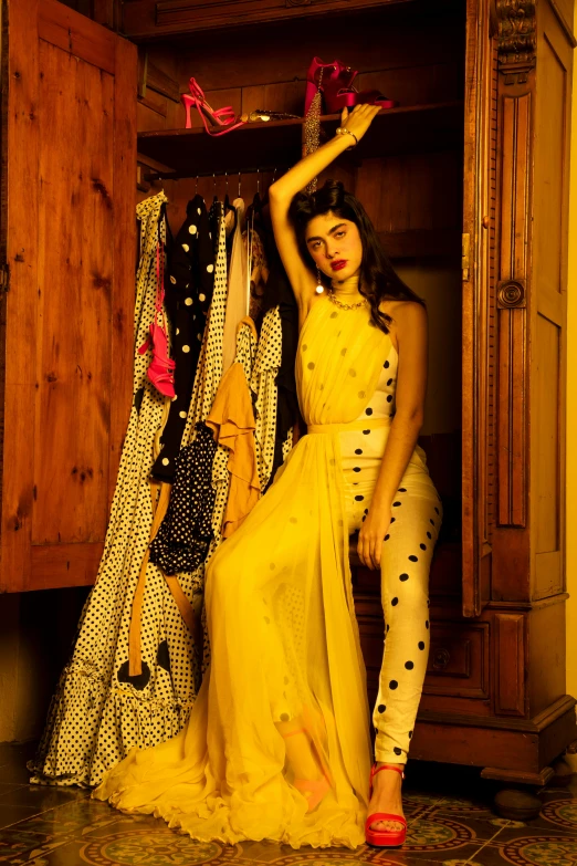 a lady wearing yellow posing in front of clothes