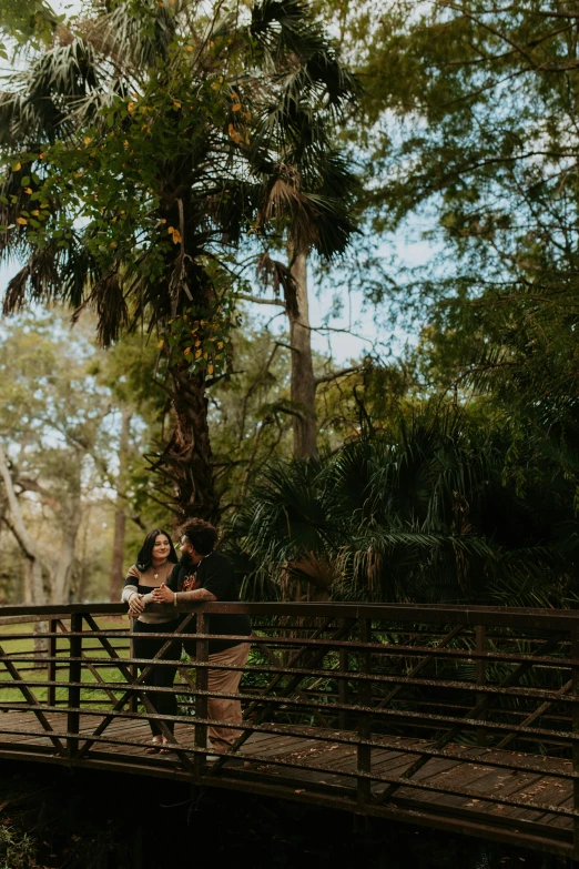 the couple is standing on the bridge in the park