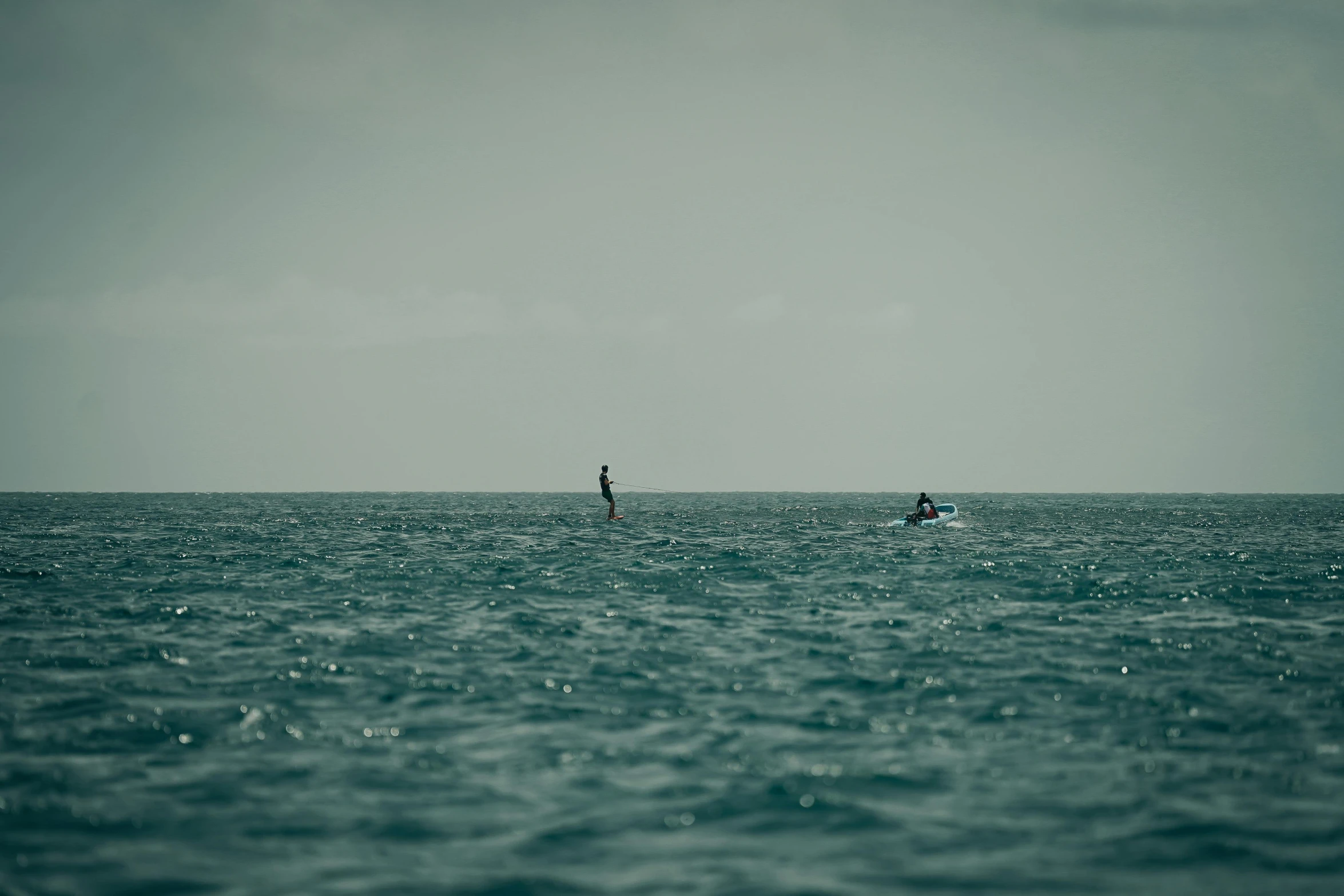 two people riding boards in the ocean while kitesurfing