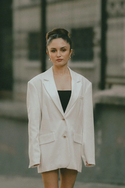 a woman in a short skirt and white jacket walking down the street