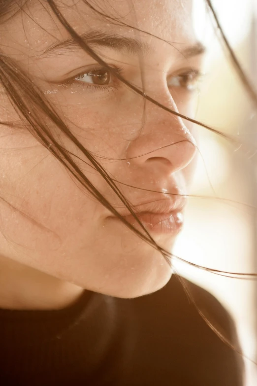 the hair on a young woman is blowing in the wind