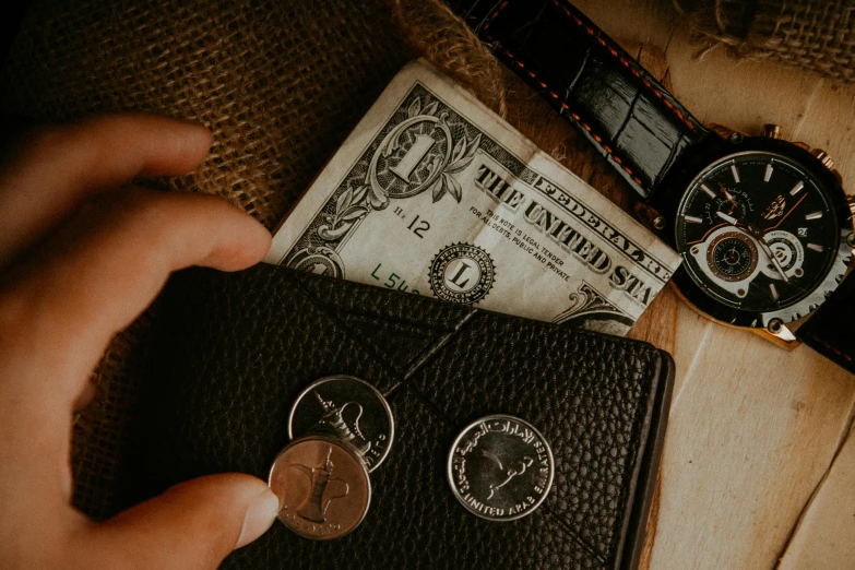 there are two coins being held next to a watch