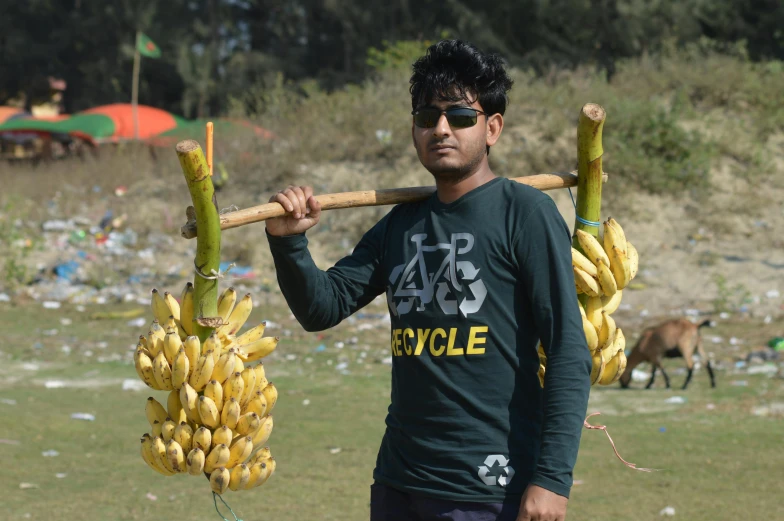 a man is carrying bananas on a stick