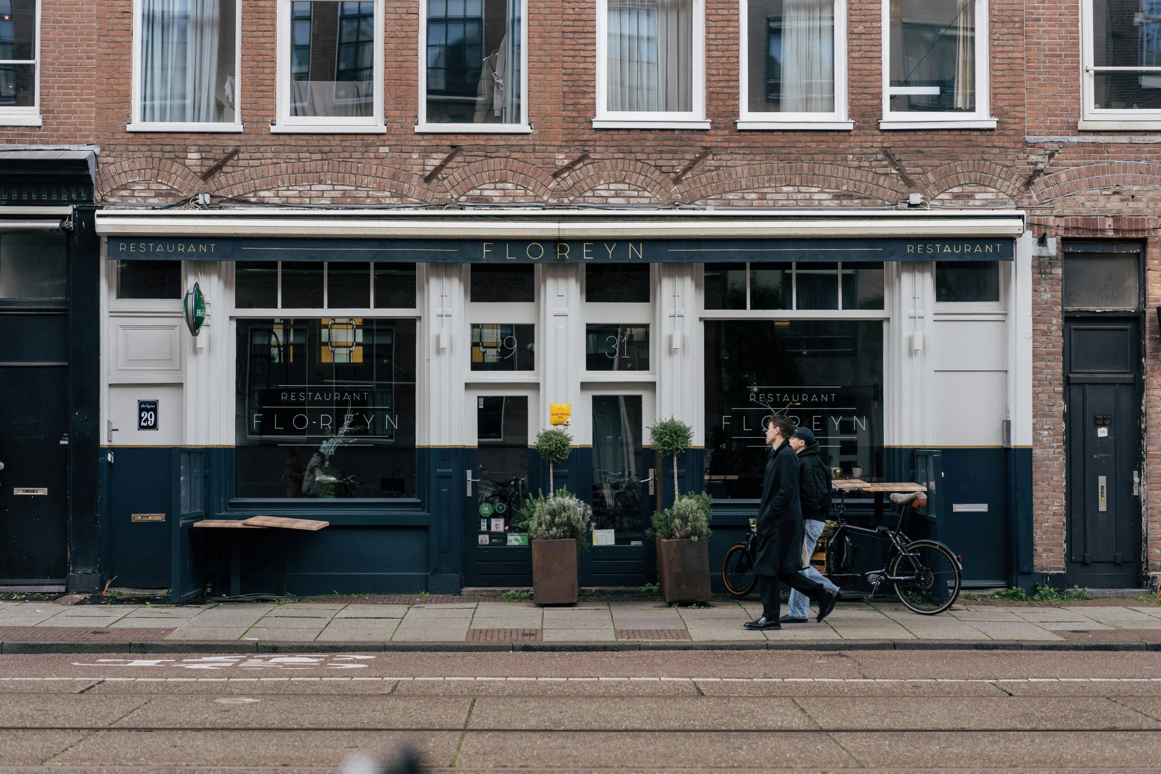 a man walks down the street past a cafe