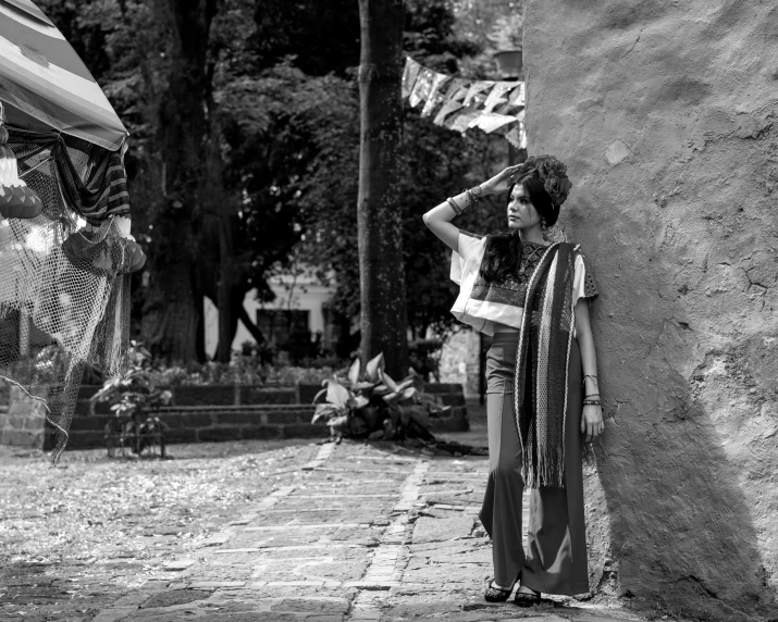 woman leaning against stone wall with flag hanging in background