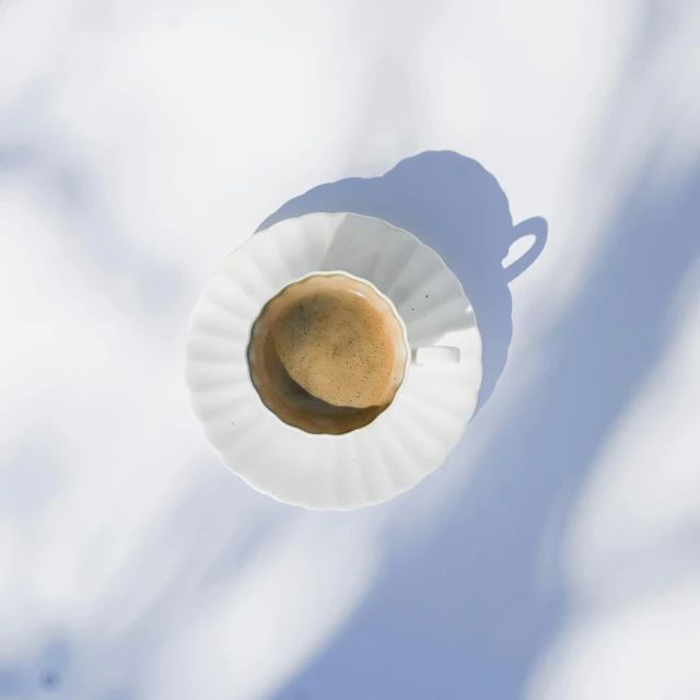 a white cup with a saucer is in the air